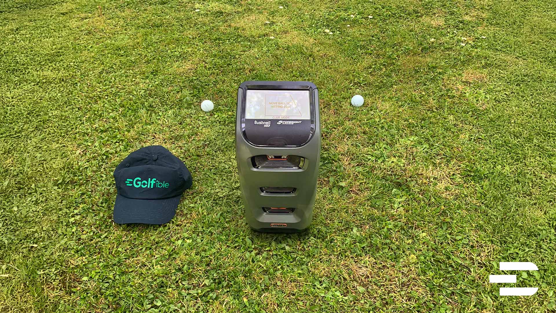Bushnell Launch Pro set up outdoors on grass with Golfible hat