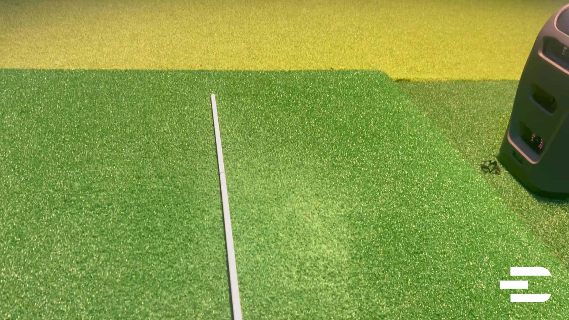 Bushnell Launch Pro with alignment stick placed for automatic calibration on hitting mat.