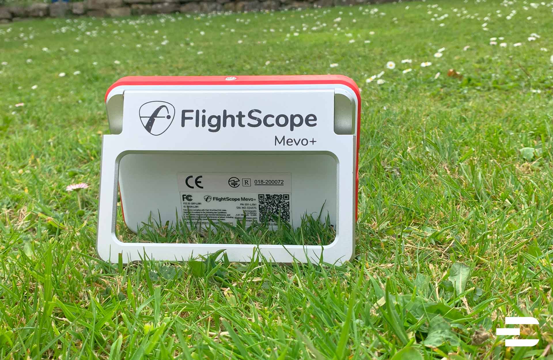 FlightScope Mevo Plus launch monitor positioned on grass behind hitting area for outdoor golf tracking